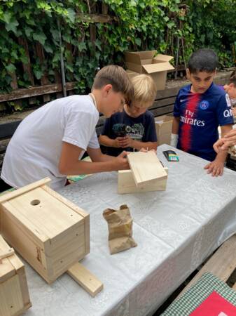 Das Bild ist beim Nachmittag im Gemeinschaftsgarten entstanden. Kinder bauen gemeinsam einen Nistkasten aus Holz.
