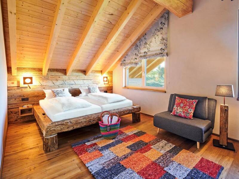 Massives Holzbett im gemütlichen Dachgeschoss-Schlafzimmer des Schwarzwald Chalets.