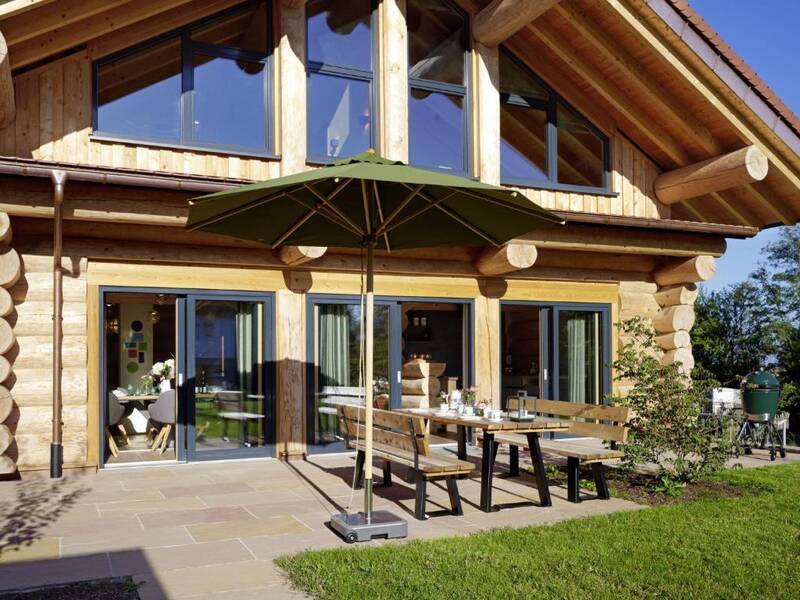 Der große Tisch auf der Holzterrasse am Schwarzwald Chalet mit Blick in den Garten.