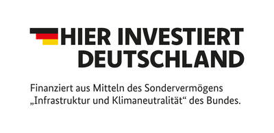 Auf dem Bild steht in großer Schrift "Hier investiert Deutschland", begleitet von einem Text, der angibt, dass die Finanzierung aus dem Sondervermögen "Infrastruktur und Klimaneutralität" des Bundes stammt, sowie den Farben der deutschen Flagge.