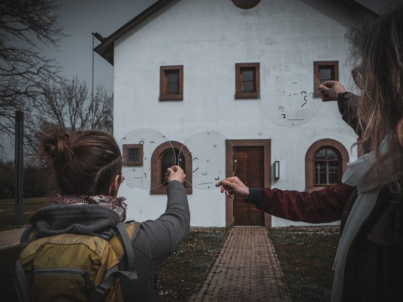 Drei Personen halten runde, mit Symbolen versehene Glasscheiben in die Höhe.