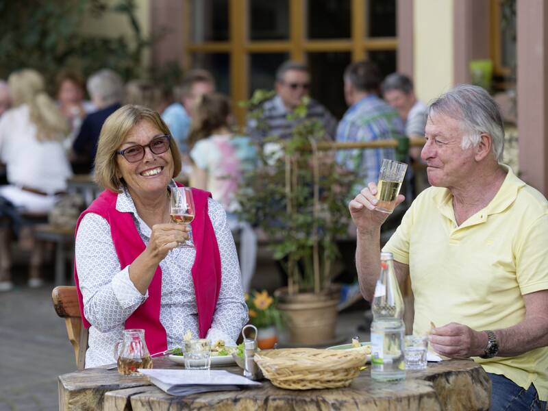 Zwei Gäste sitzen bei Wein und Essen auf der Terrasse der Sulzbach-Straußi.